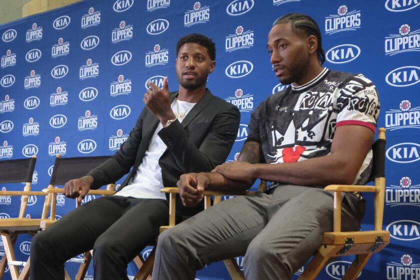Paul George, left, and Kawhi Leonard take their place on the podium before the start of the Clippers' intorductory news conference.