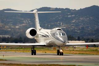 A jet taxis onto a runway in preparation for take off, within view of the Hollywood Hills.