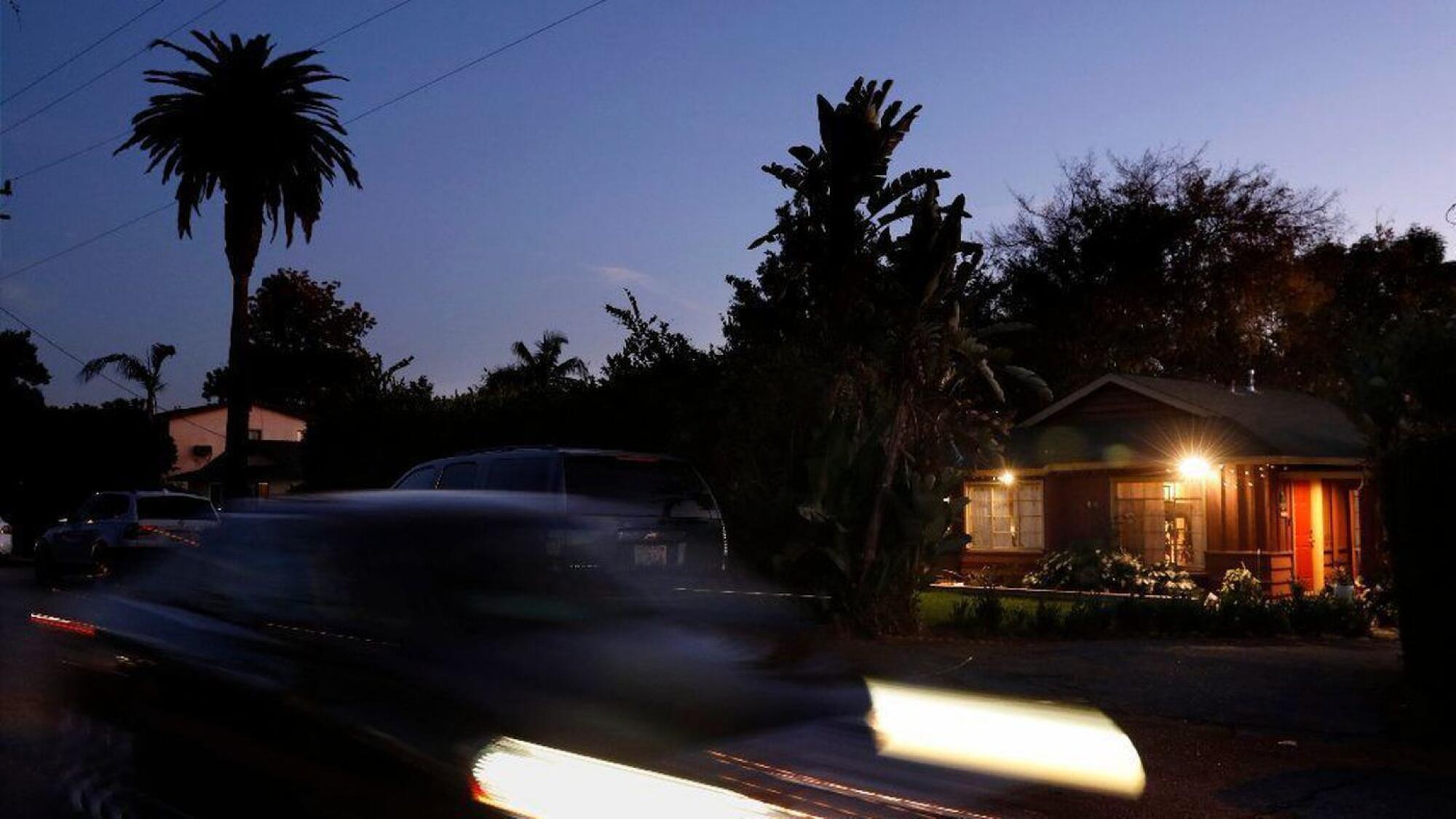A car and its headlights form a blur in front of the Altadena duplex where the baby died.