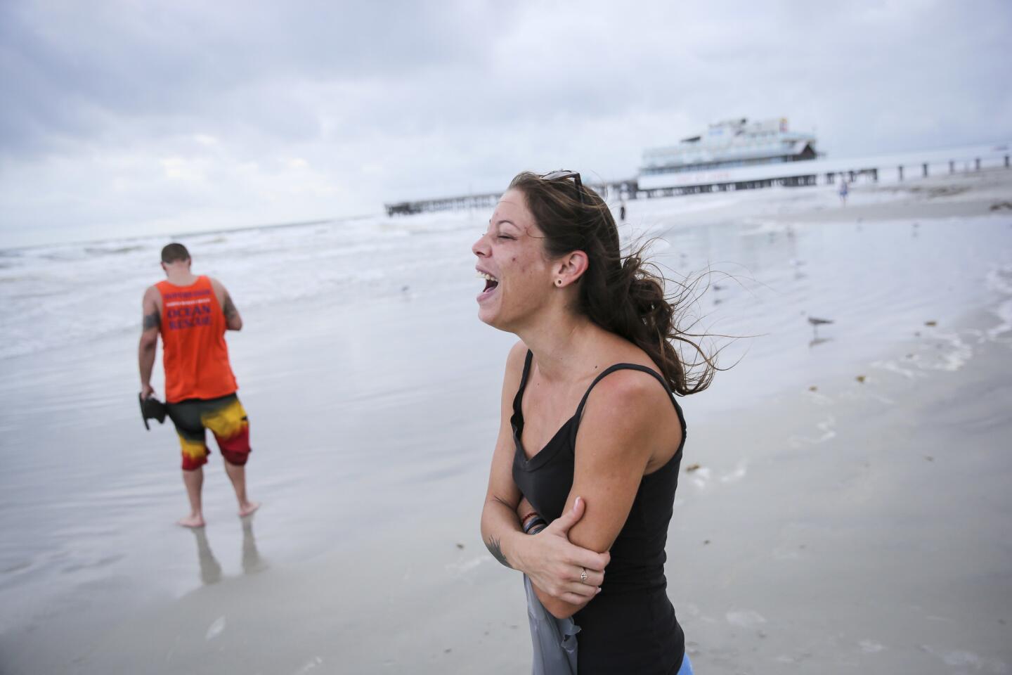 Emily Vulpi, 29, laughs as the winds pick up as she walks along the beach with Ryan Bell, 28, ahead of Hurricane Matthew in Daytona Beach, Fla. on Thursday, Oct. 6, 2016. Matthew steamed toward Florida with winds of 140 mph Thursday as hundreds of thousands of people across the Southeast boarded up their homes and fled inland to escape the most powerful storm to threaten the Atlantic coast in more than a decade. (Will Vragovic /Tampa Bay Times via AP)