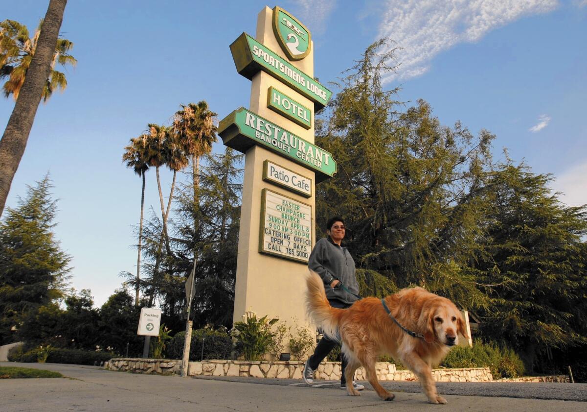A woman walks her dog along Ventura Boulevard past the landmark Sportsmen's Lodge in Studio City.