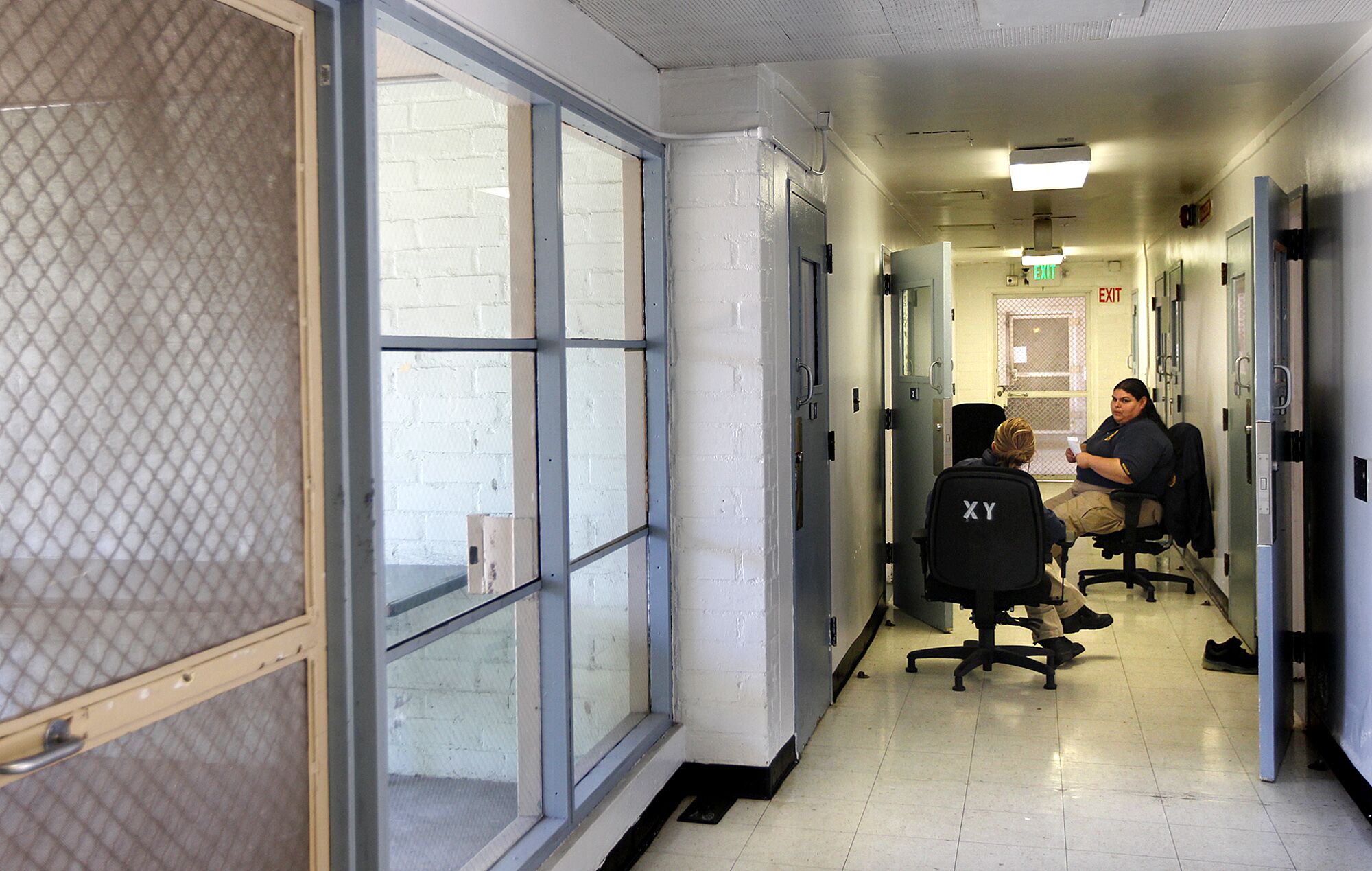 Two officers seated in a hallway of a detention center