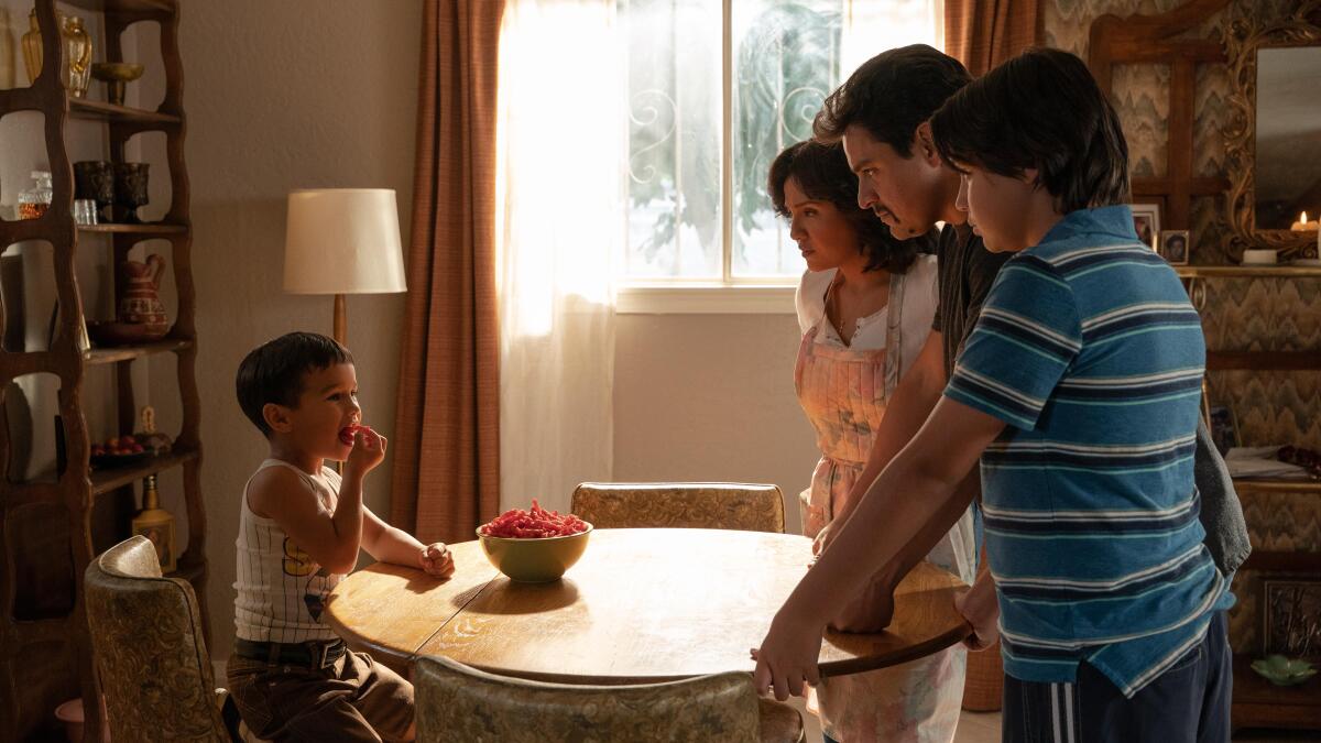 A group of people look across a table at a small child in “Flamin' Hot.”