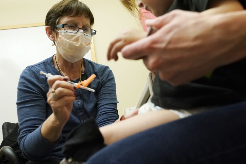 Deborah Sampson, left, a nurse at a University of Washington Medical Center clinic in Seattle, gives a Pfizer COVID-19 vaccine shot to a 20-month-old child, June 21, 2022, in Seattle. The U.S. on Thursday, Dec. 8, 2022 open doses of the updated COVID-19 vaccines for most children younger than age 5. The Food and Drug Administration's decision aims to better protect the littlest kids from severe COVID-19 at a time when children’s hospitals already are packed with tots suffering a variety of other respiratory illnesses, too. (AP Photo/Ted S. Warren, file)