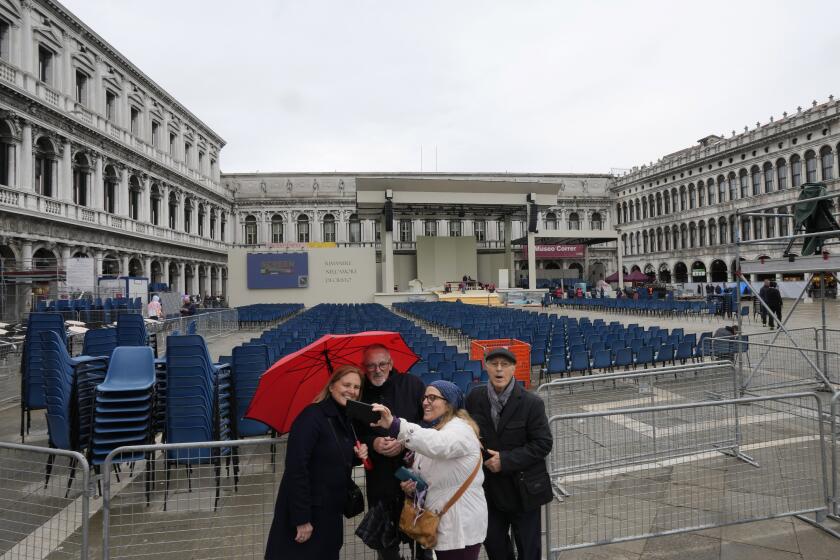 People take a selfie in front of the altar where on Sunday Pope Francis will celebrate a Mass in St. Mark Square, in Venice, Italy, Saturday, April 27, 2024. (AP Photo/Antonio Calanni)