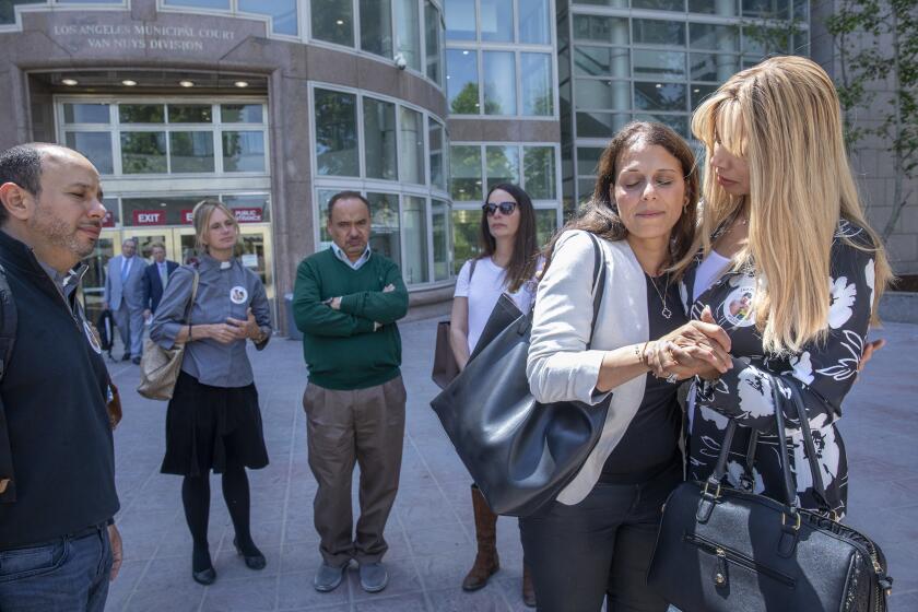 VAN NUYS, CA-APRIL 25, 2022: Nancy Iskander, 2nd from right, is consoled by a friend outside of Van Nuys Courthouse during a lunch break from a preliminary hearing for Rebecca Grossman who is charged with murder and other counts stemming from a crash in Westlake Village that left Iskander's sons Mark Iskander, 11, and Jacob Iskander, 8, dead. At far left is her husband Karim. Nancy Iskander took the witness stand and testified to the moment her sons were killed by Grossman's Mercedes as they were walking in the crosswalk on Triunfo Canyon Rd. In. Westlake. Village. (Mel Melcon / Los Angeles Times)
