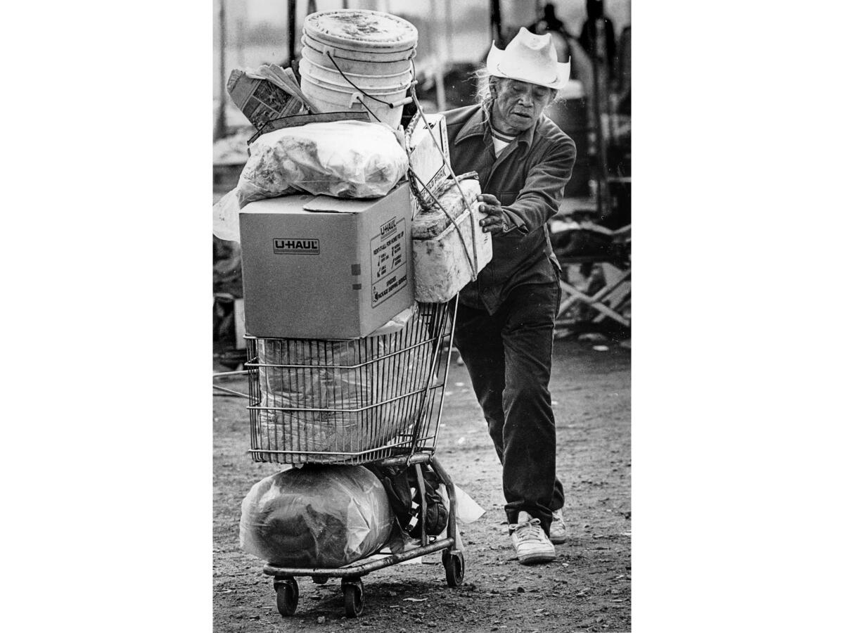 Sep. 25, 1987: With his belongings piled on a shopping cart, Alfred Gueva leaves the encampment where he had lived since it opened in June.