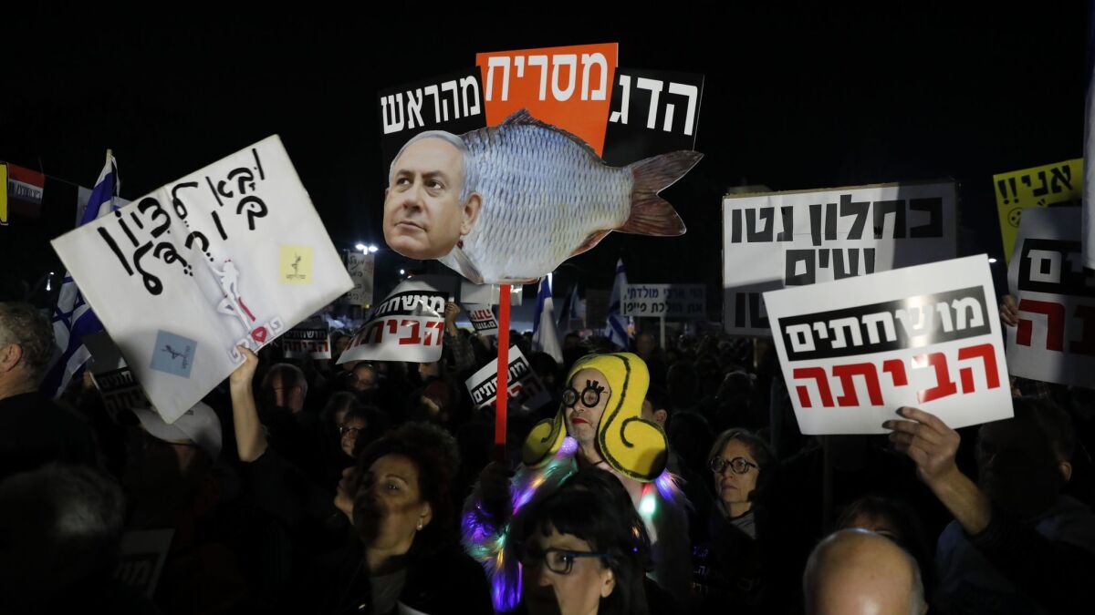Israeli protesters hold signs in Hebrew reading, "The fish stinks from the head," on Jan. 13, 2018, during a weekly protest in Tel Aviv against government corruption.