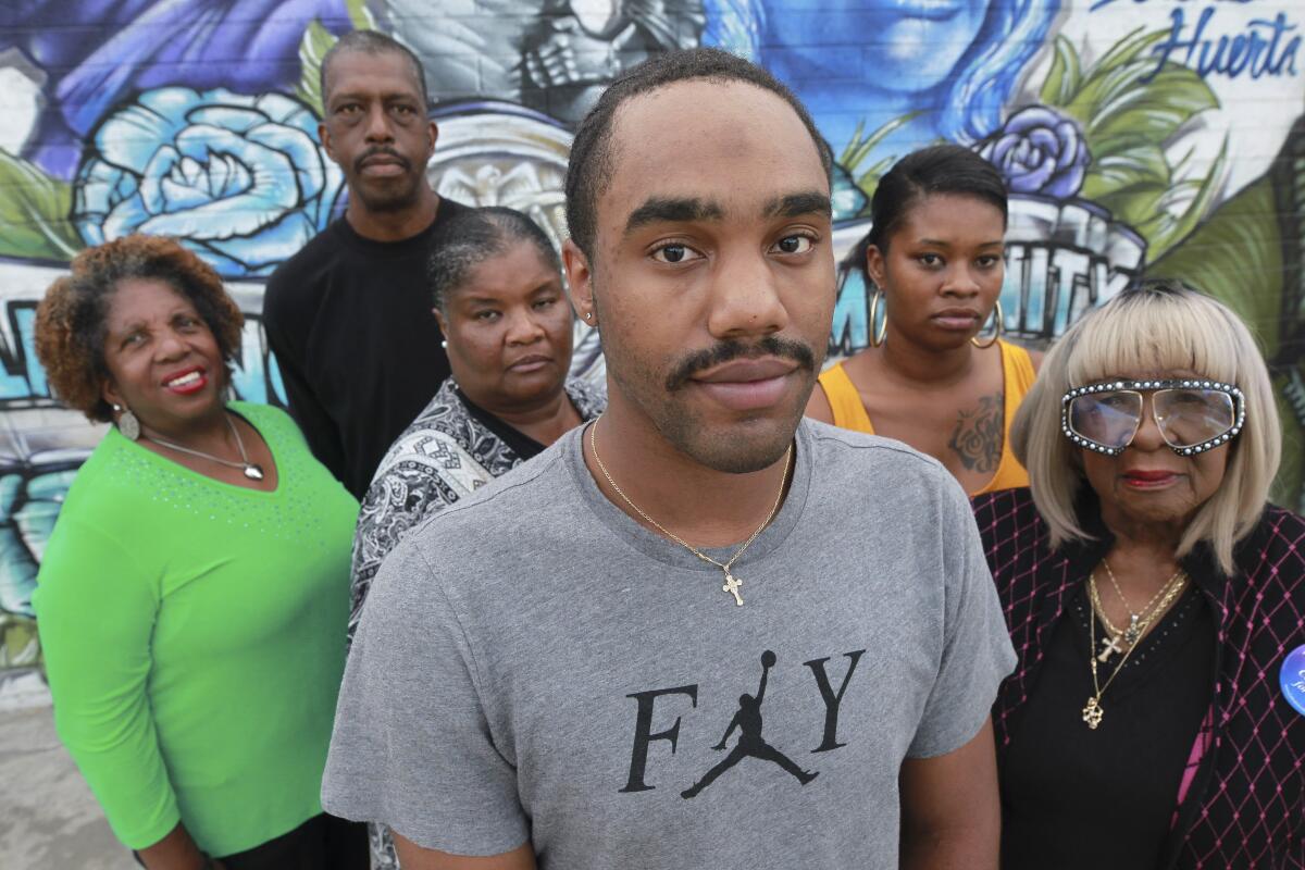 Miguel Lucas, center, who was bitten in the face by a cellmate while incarcerated in San County jail, with the family of Reginald Harmon Jr., the man who assaulted him, from left, aunt Donnetta Moore, father Reggie Harmon Sr., mother Alicia Muhammad, sister Samatha Harmon, and grandmother Kathleen Harmon, in Encanto on Wednesday, October 16, 2019.