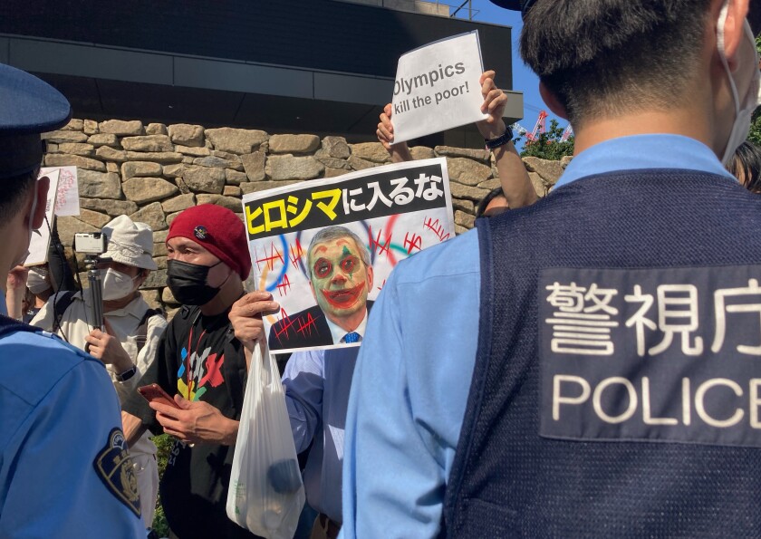 Protesters against the Olympic and Paralympic Games (Tokyo 2020) confront police officers in Tokyo, Saturday, July 10, 2021. The poster, center, reads, "Don't enter Hiroshima," with a picture of International Olympic Committee President Thomas Bach and graffiti over his face, as local media report Bach is scheduled to visit Hiroshima later this month ahead of the 2020 Summer Olympics starts. (AP Photo/Kwiyeon Ha)