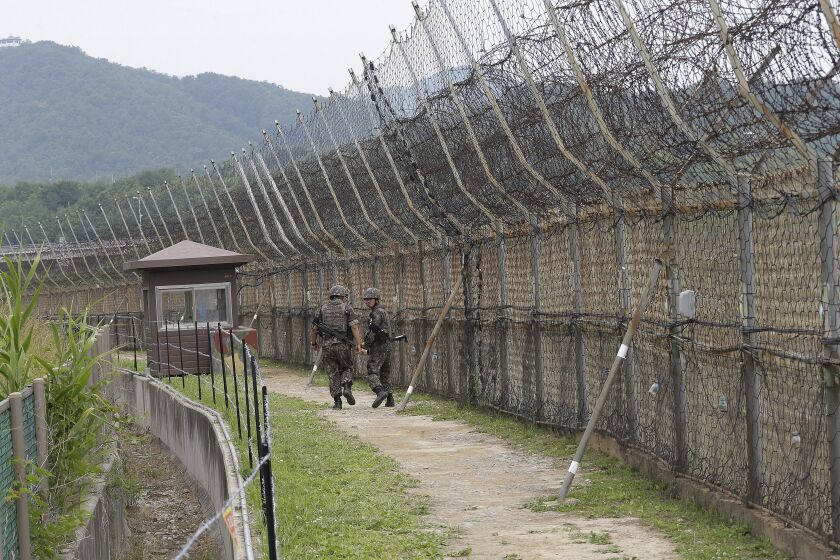 FILE - In this June 14, 2019, file photo, South Korean army soldiers patrol while hikers visit the DMZ Peace Trail in the demilitarized zone in Goseong, South Korea. South Korean troops were engaged in an operation near the heavily fortified border with North Korea on Wednesday, Nov. 4, 2020, after detecting "unidentified personnel" there, the South's military said. (AP Photo/Ahn Young-joon, File)