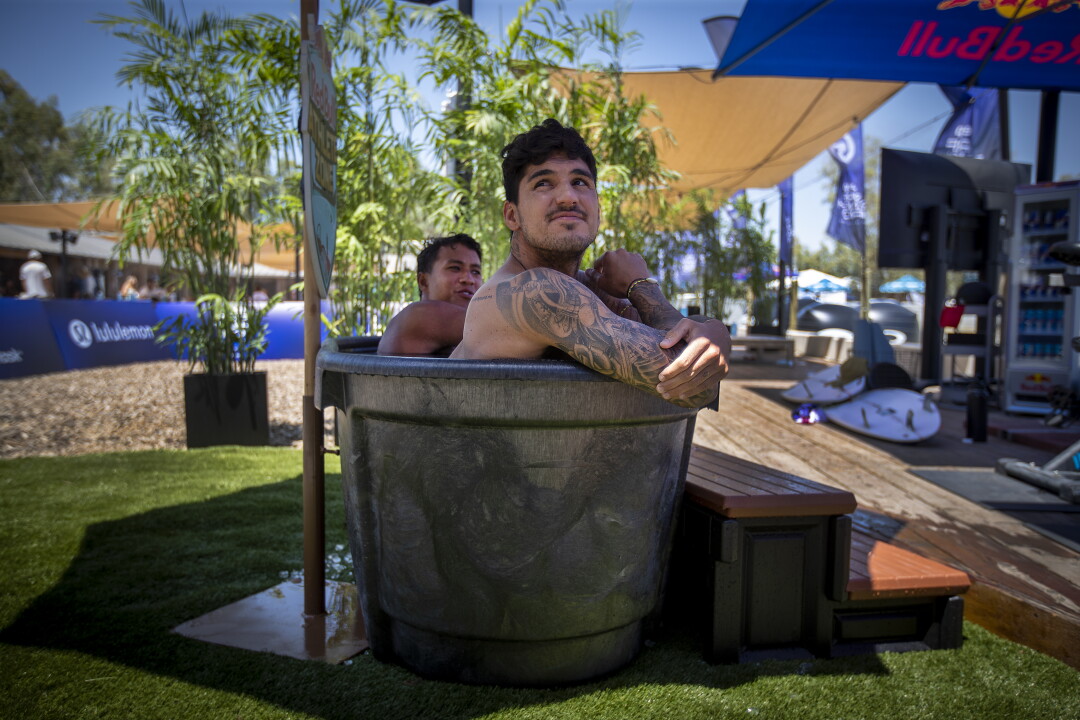 Gabriel Medina, avant, double champion du monde WSL du Brésil, et Seth Muniz, d'Hawaï, sont assis dans la piscine de glace.