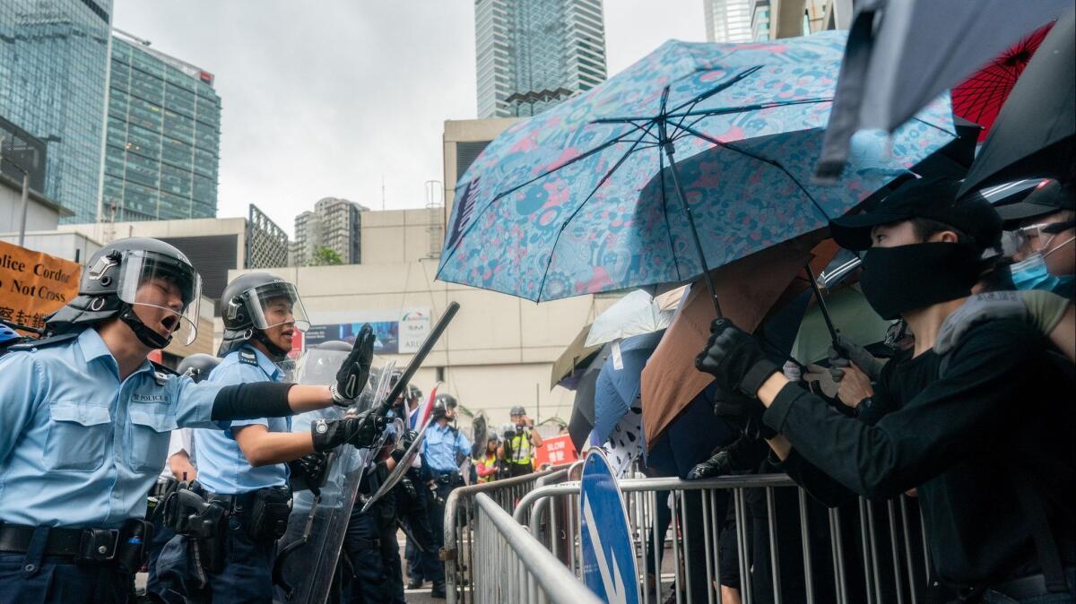 Police officers stand guard as protesters block a street near the government headquarters during a rally against the extradition bill on June 12 in Hong Kong.