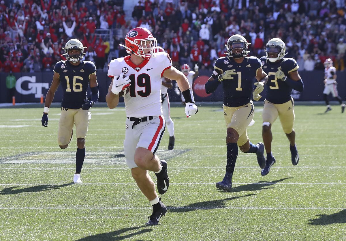 Georgia tight end Brock Bowers looks over his shoulder at Georgia Tech defenders as he heads to the end zone for a touchdown reception during the second quarter of an NCAA college football game on Saturday, Nov. 27, 2021, in Atlanta. (Curtis Compton/Atlanta Journal-Constitution via AP)