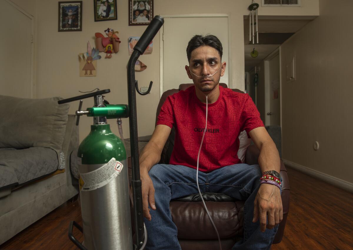 Leobardo Segura Meza sits at home with his oxygen tank.