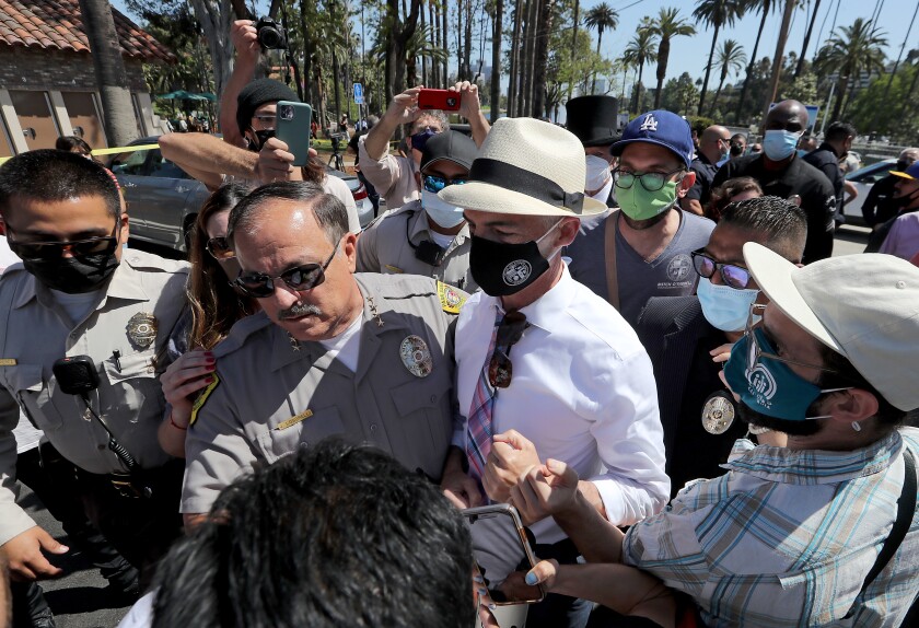 Echo Park Lake reopens, with new grass, new paint and no
tents 2 Police officers escort L.A. City Councilman Mitch O'Farrell as he is heckled by homeless advocates and Echo Park residents