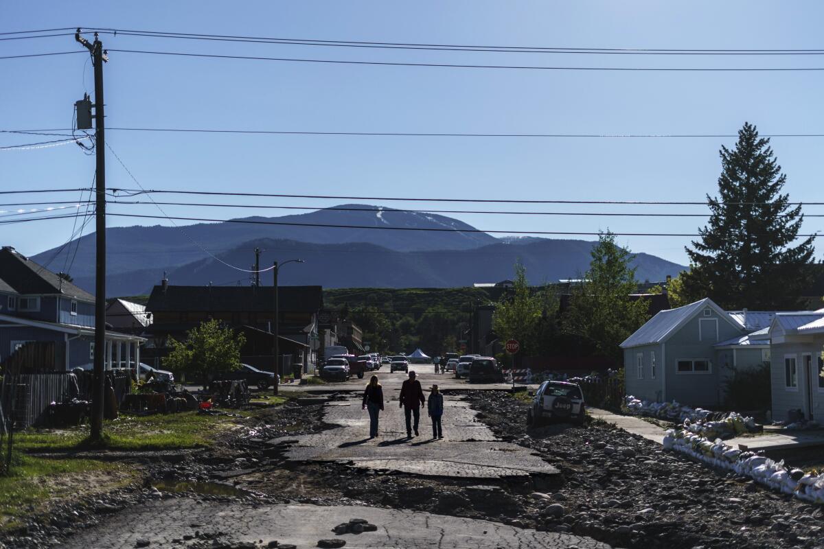 Pedestrians walk down a street washed away by floodwaters.