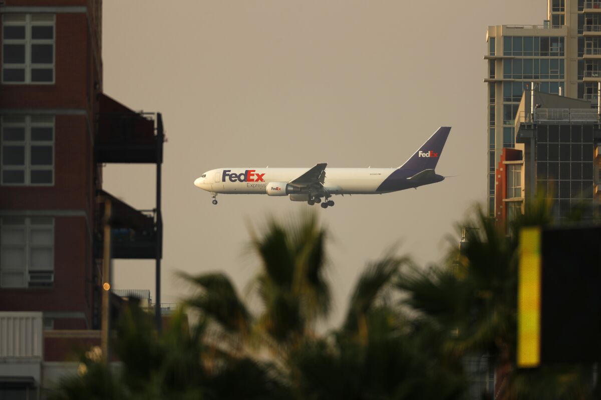 A FedEx 767 airplane framed between buildings. 