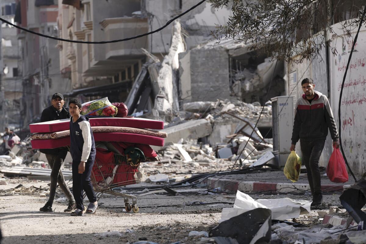 Palestinos caminan por zonas destrozadas por bombardeos israelíes en el campo de refugiados 