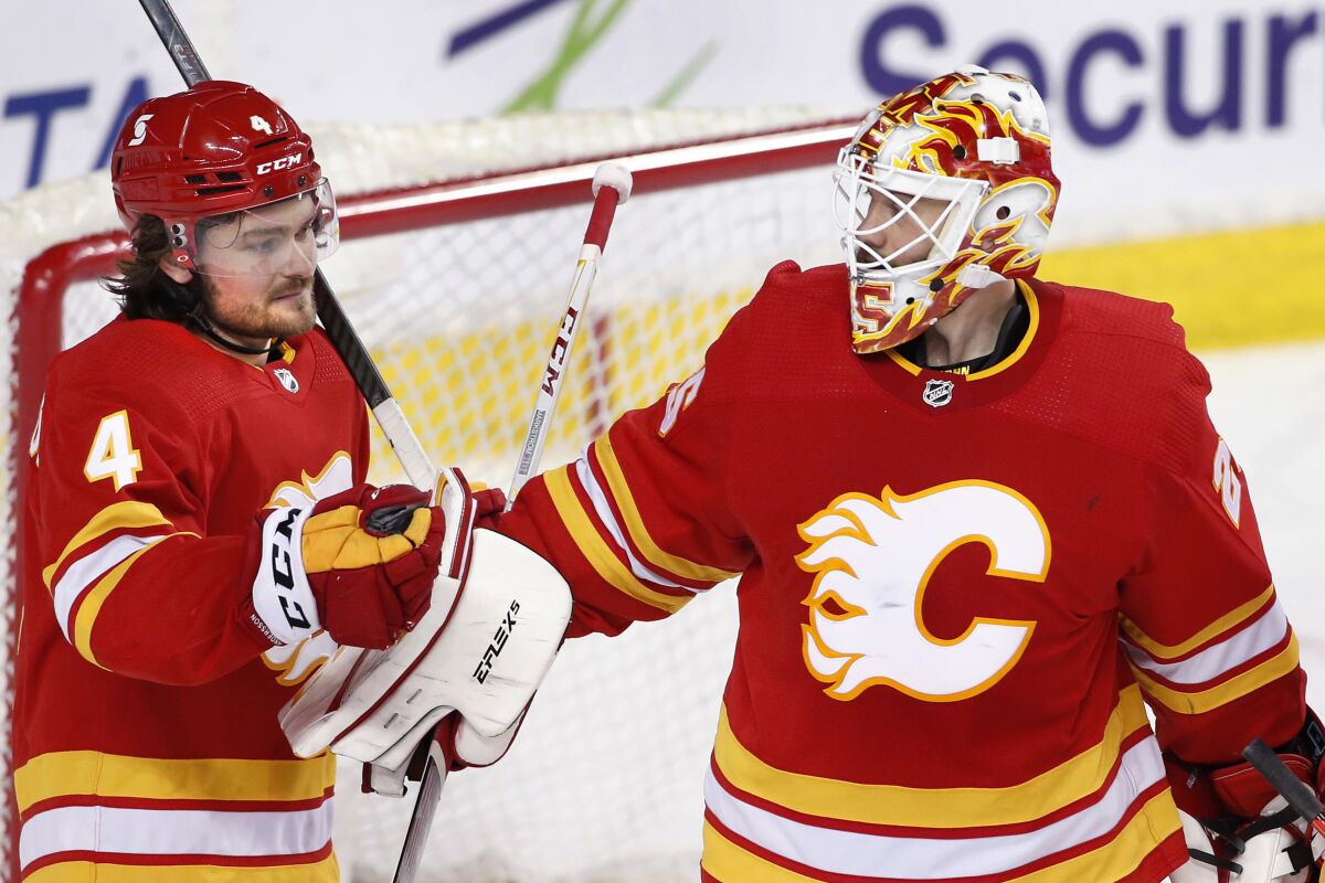 Calgary Flames goalie Jacob Markstrom, right, is congratulated by Rasmus Andersson after the team's 6-1 victory over the Ottawa Senators in an NHL hockey game Sunday, May 9, 2021, in Calgary, Alberta. (Larry MacDougal/The Canadian Press via AP)