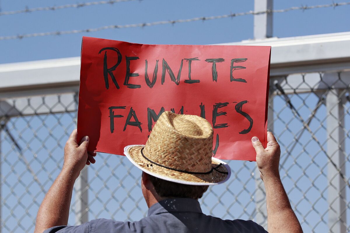 A protester holds a sign saying "Reunite Families" outside a gate at the Port of Entry facility in Fabens, Texas