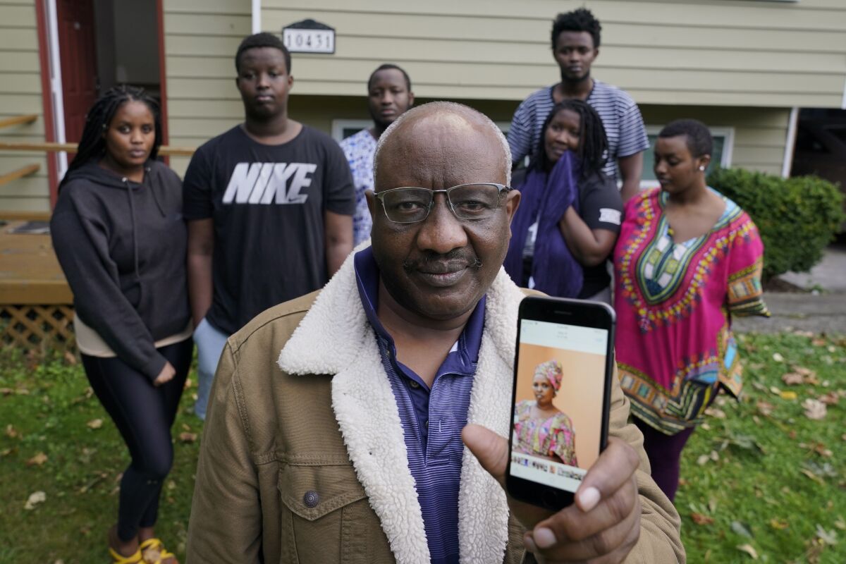 Sophonie Bizimana at his home in Kirkland, Wash., along with six of his children as he displays a photo of his wife.