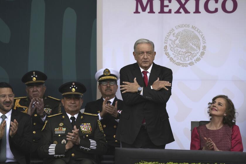 Mexico's President Andrés Manuel López Obrador, accompanied by first lady Beatriz Gutiérrez Müller, sends out a symbolical embrace at the start of the annual Independence Day parade in the capital's main square, the Zocalo, in Mexico City, Saturday, Sept. 16, 2023. (AP Photo/Fernando Llano)