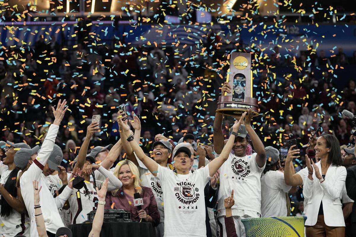 FILE - South Carolina head coach Dawn Staley celebrates with her team after a college basketball game in the final round of the Women's Final Four NCAA tournament against UConn, Sunday, April 3, 2022, in Minneapolis. South Carolina won 64-49 to win the championship. The number of women competing at the highest level of college athletics continues to rise along with an increasing funding gap between men’s and women’s sports programs, according to an NCAA report examining the 50th anniversary of Title IX. (AP Photo/Eric Gay, File)