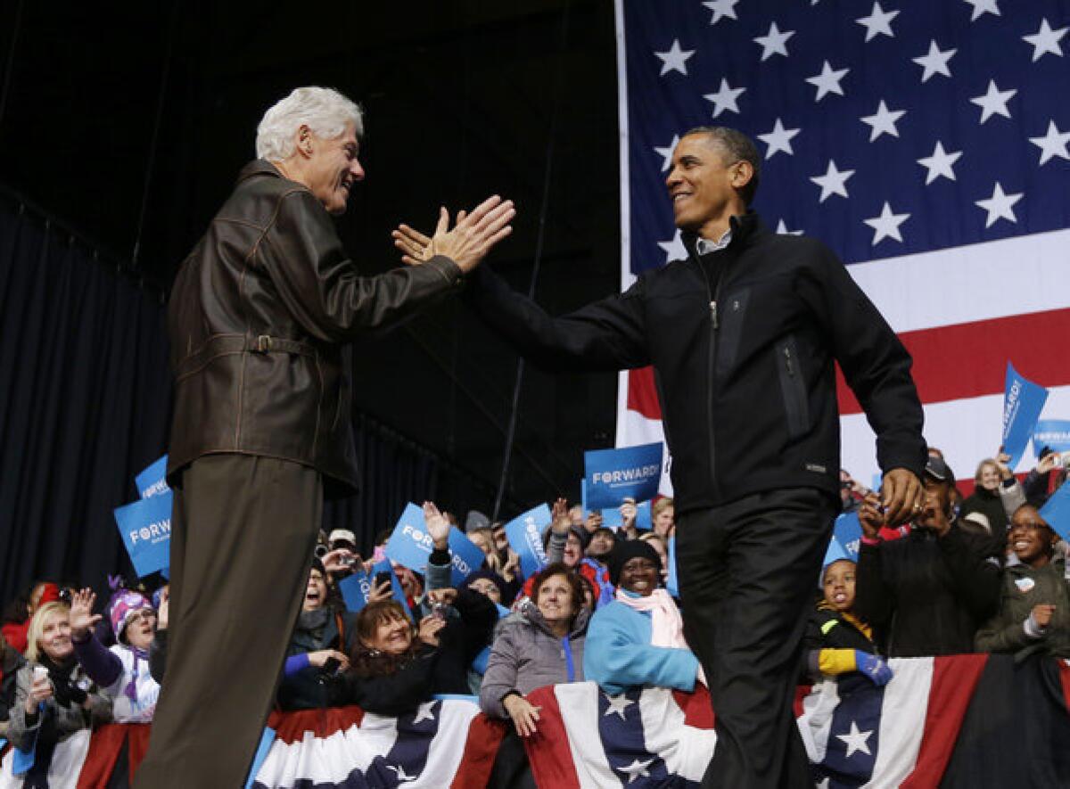 Former President Bill Clinton greets President Obama at a late-night campaign rally in Bristow, Va.