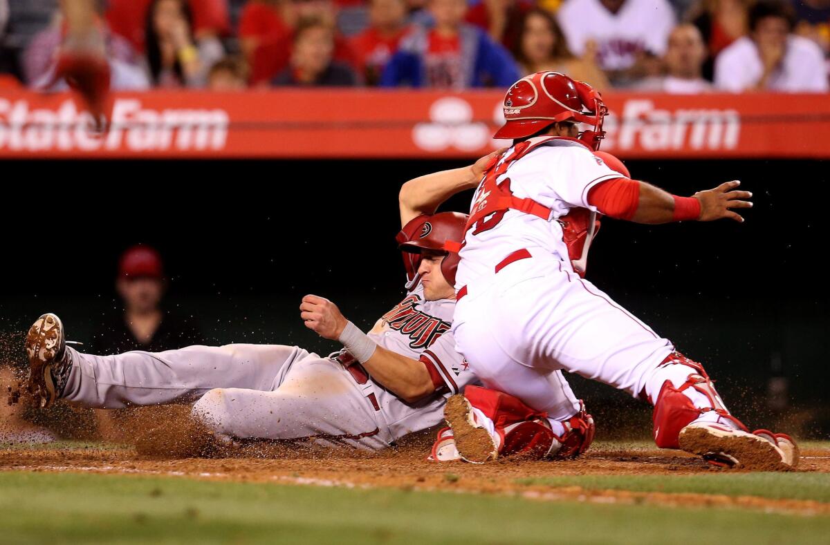 Angels catcher Carlos Perez tries to tag out Diamondbacks baserunner Nick Ahmed after A.J. Pollack flew out to right fielder Kole Calhoun in the ninth inning.