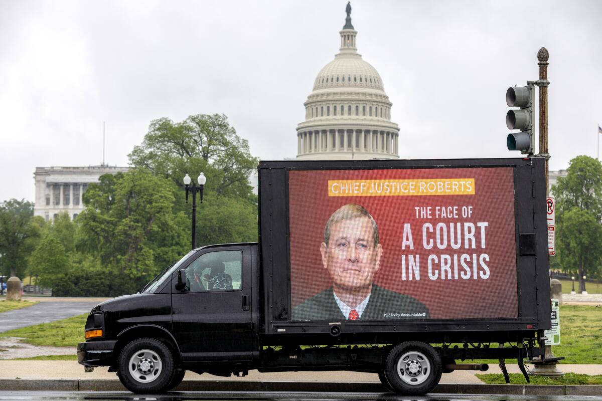 A mobile billboard showing Chief Justice John Roberts and a sign "The face of the court in crisis" 