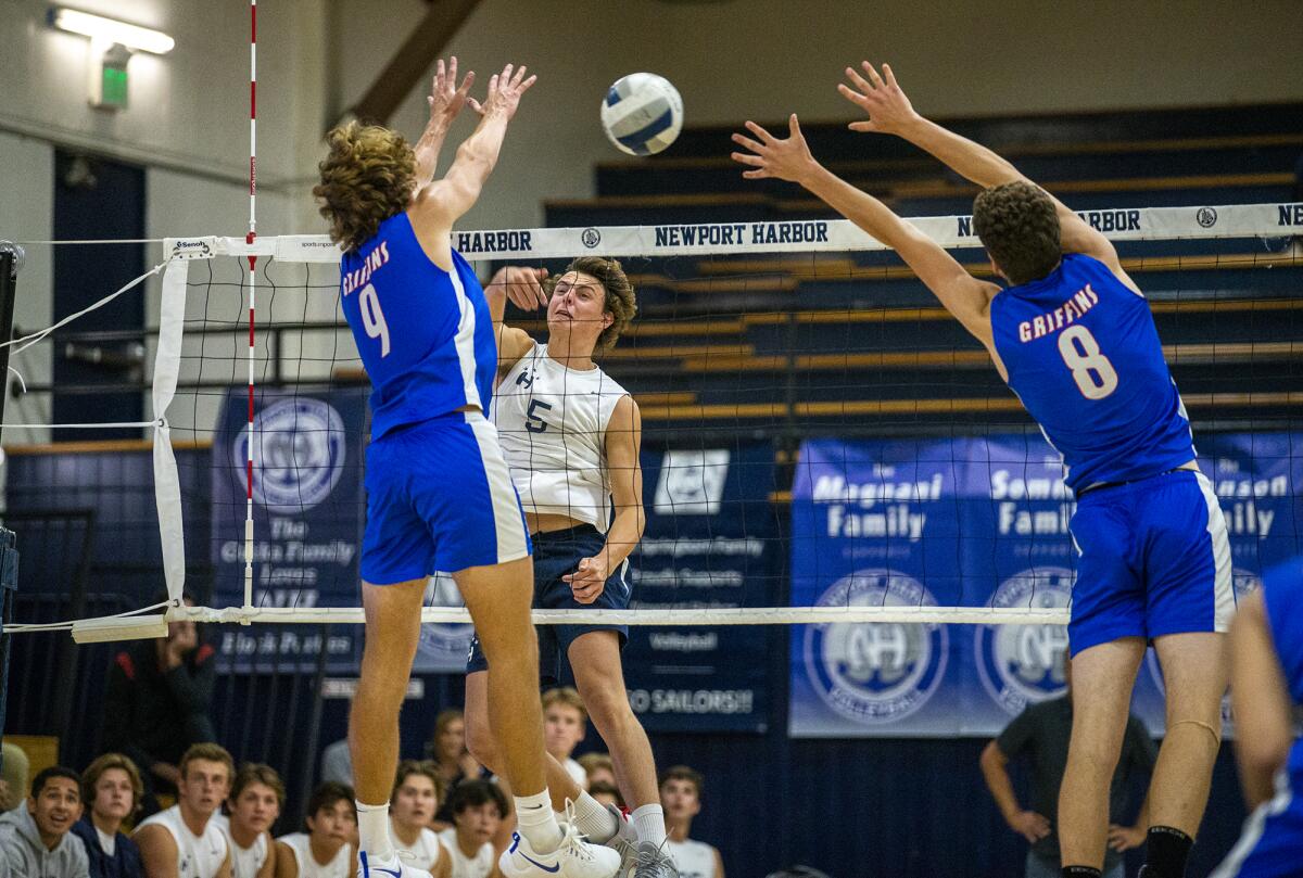 Newport Harbor's Riggs Guy hits against Los Alamitos' Noah Roberts, left, and Beck Weber on Tuesday.