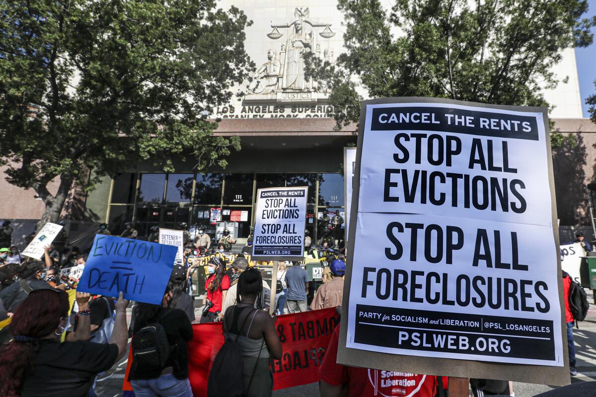 People demonstrate outside an L.A. courthouse with signs that read "Stop all evictions" and "eviction = death"