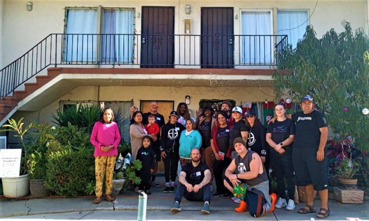 Volunteers with Love Costa Mesa and Luv in Motion pose with locals whose homes were decorated.