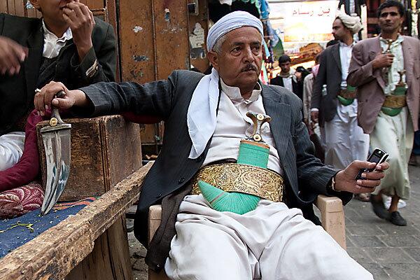 Shalan bin Yehaye Hbubari in front of his jambiya stall, one of dozens he oversees. "I refuse to sell those knockoffs. I get sad when I see them," says Hbubari, gripping a rhino-handled dagger. "This will endure forever."