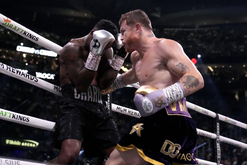 Canelo Álvarez delivers a punch while Jermell Charlo leans on the ropes during their super middleweight title bout