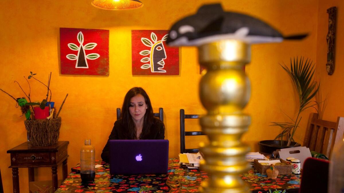 Gabriela Cowperthwaite works on her computer in her dining room at her home is Los Angeles,