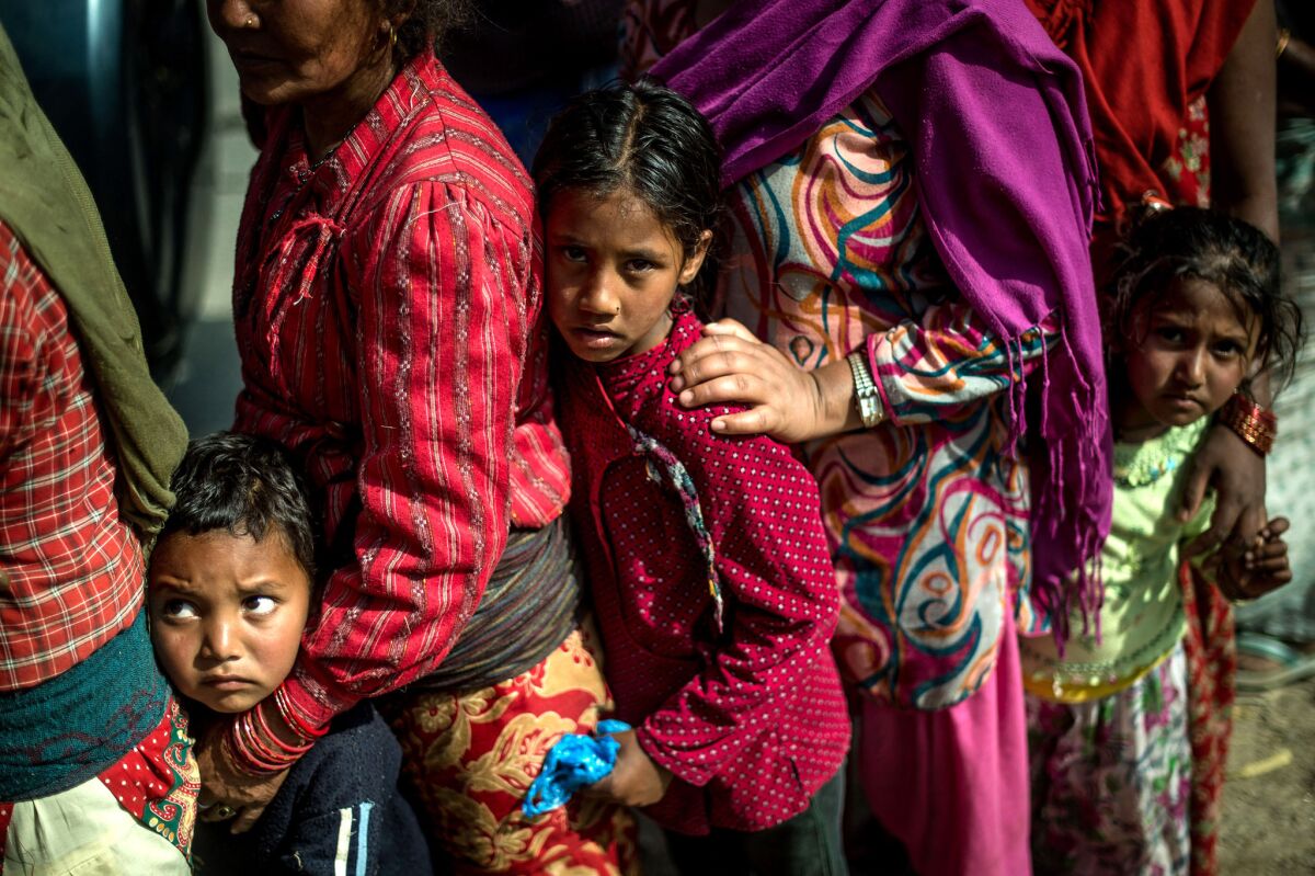 Victims of the Nepal earthquake line up along a road as they wait to receive food and goods at an aid distribution point in Bhotechaur on Friday.
