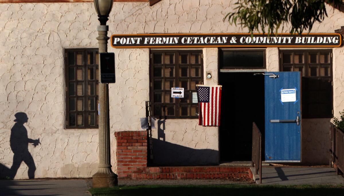 A bill in the California Legislature intended to boost election turnout has been delayed. Above, a voter casts a lone shadow on the wall while approaching a poling place in San Pedro last year.