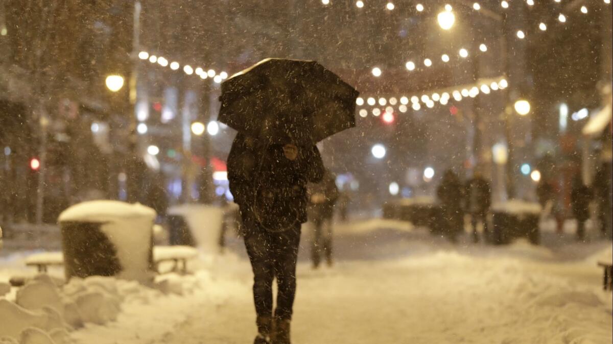A person walks beneath an umbrella as snow falls in downtown Jersey City, N.J.