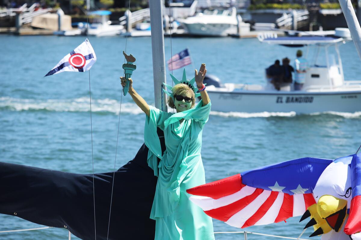 A woman dressed as the Statue of Liberty waves during the Old Glory Fourth of July Boat Parade.