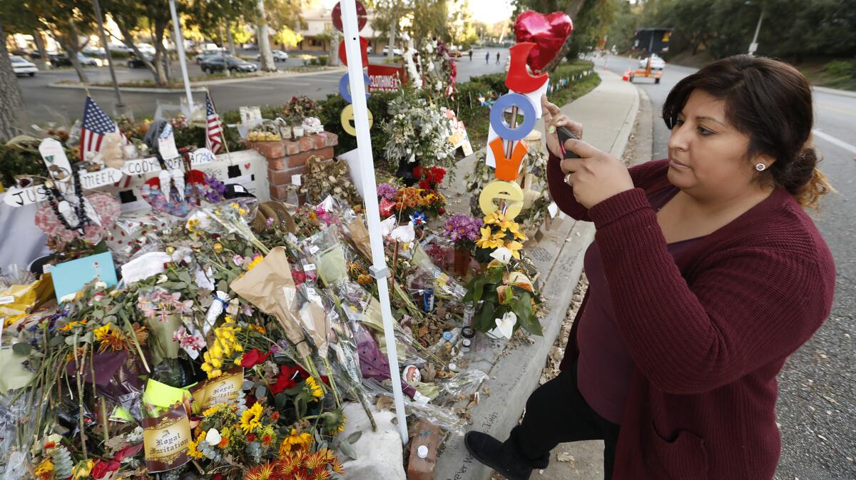 Vanessa Guzman from Palmdale takes photographs at the growing memorial at Moorpark Road and West Rolling Oaks Drive in Thousand Oaks near the Borderline shooting scene.