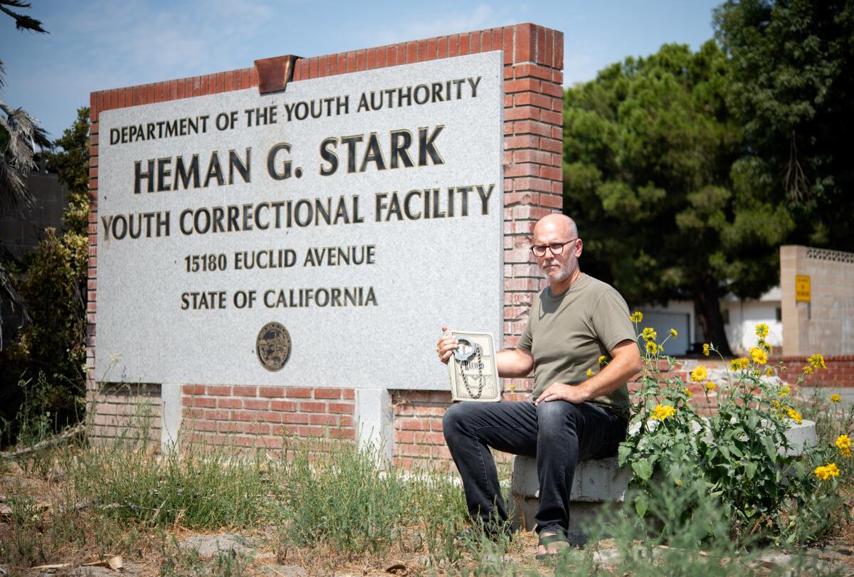 David Reeve holds handcuffs and a logbook outside of Youth Training School.