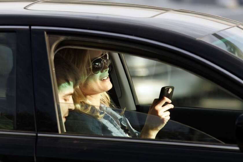 This driver is using her cellphone while trying to focus on the road ahead. A new study quantifies the risk of this and other types of distracted driving.