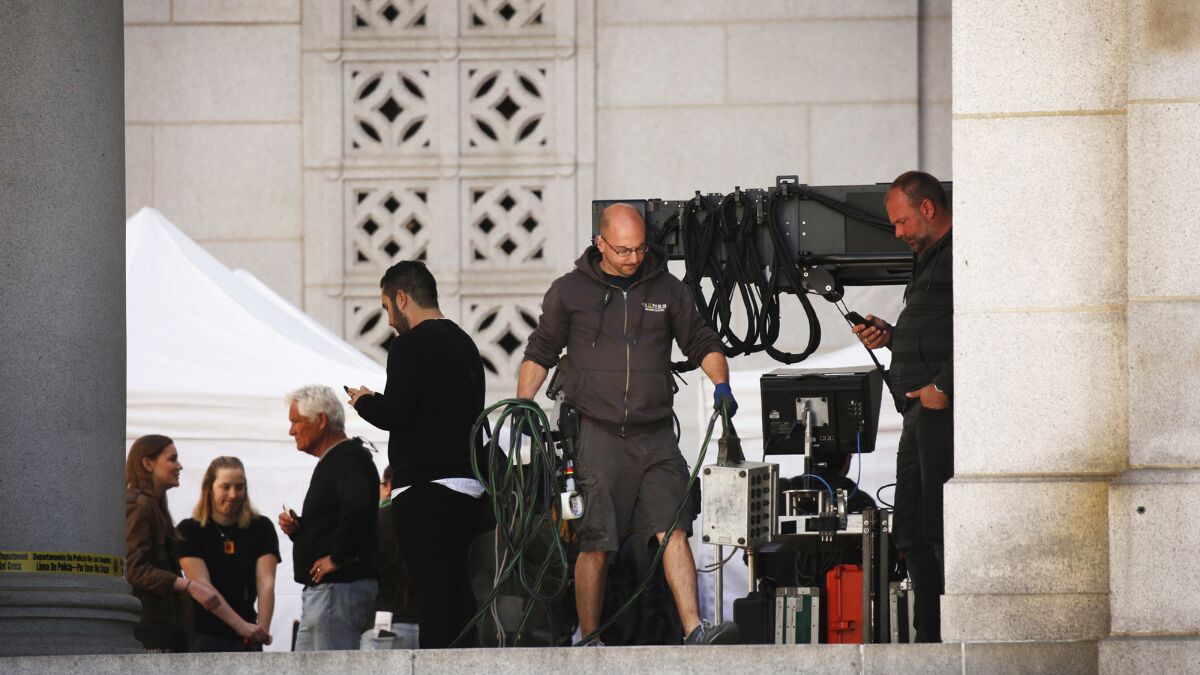A film crew works on the film "Ocean's Eight" as it shoots outside Los Angeles City Hall.