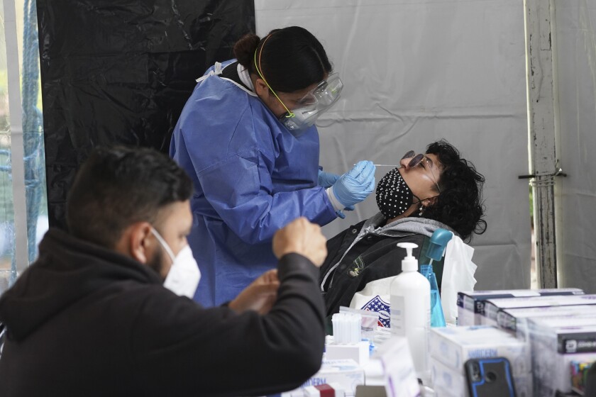 A health worker collects a sample from a person being tested for COVID-19 at the Miguel Hidalgo borough of Mexico City, Tuesday, Jan. 11, 2022. (AP Photo/Marco Ugarte)