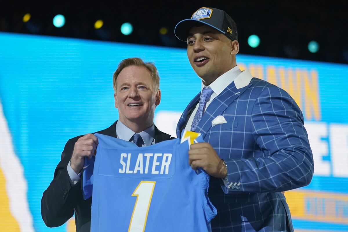 Northwestern tackle Rashawn Slater, right, holds a team jersey with NFL Commissioner Roger Goodell after the San Diego Chargers selected him with the 13th pick in the NFL football draft Thursday April 29, 2021, in Cleveland. (AP Photo/Tony Dejak)