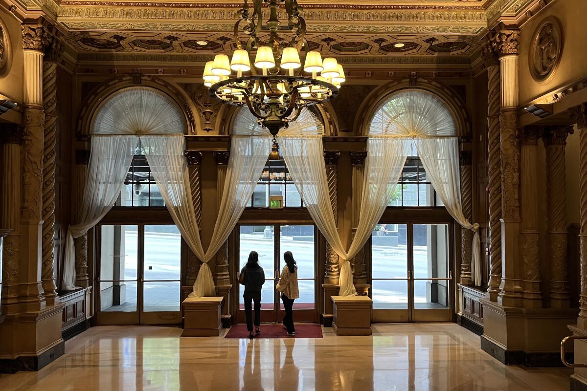 An ornate room at a downtown hotel, empty but for a couple of people