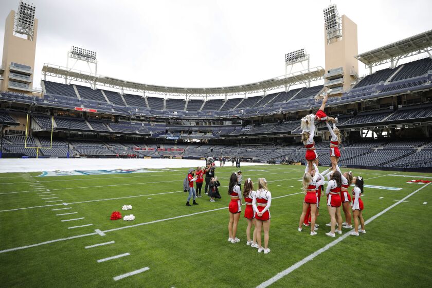 SAN DIEGO, CA - DECEMBER 28: North Carolina State cheerleaders take photos on the field at Petco Park after the Holiday Bowl was cancelled hours before kick-off because UCLA had a number of positive COVID-19 cases on the team on Tuesday, Dec. 28, 2021 in San Diego, CA. (K.C. Alfred / The San Diego Union-Tribune)
