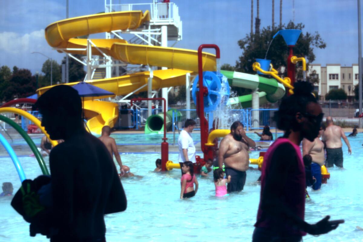 People wade in a public swimming pool.